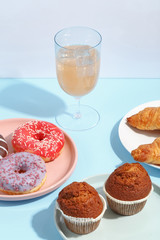 Various sweets, doughnuts, bagels, muffins and drinks on a multi-colored background. Bright colors, the concept of the holiday.