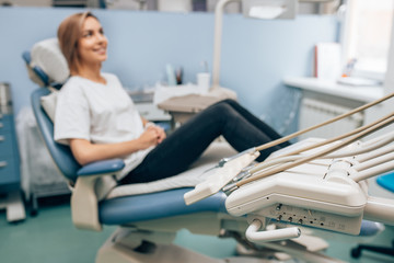 side view on young caucasian woman sitting in dental office wearing casual clothes, waiting for doctor, for medical check-up, teeth exam by professional doctor