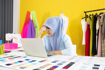 A Muslim woman use laptop for receiving order of her clients.  She is very serious and worry for detailed with the creation of the work.  Concept on designing and making product.