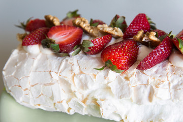 Meringue cake with mint strawberries and walnuts on a plate
