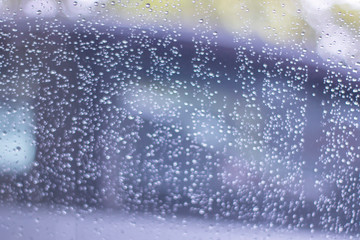 Fototapeta na wymiar Blurred, raindrops, perched on a glass after a rain background image