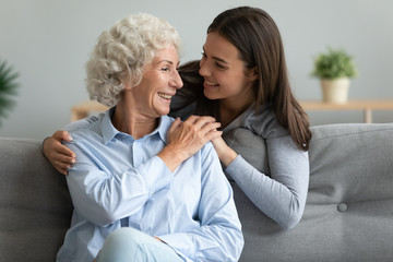 Happy grandmother and granddaughter hugging, holding hands, expressing love