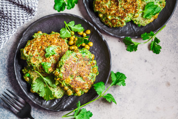 Green broccoli and pea pancakes on black plate, top view. Healthy vegan food concept.