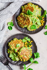 Green broccoli and pea pancakes on black plate, top view. Healthy vegan food concept.