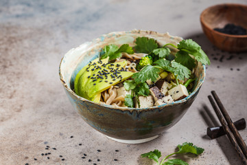 Buckwheat noodles - soba with tofu, broccoli, avocado, seedlings and cilantro, copy space. Healthy vegan food concept.
