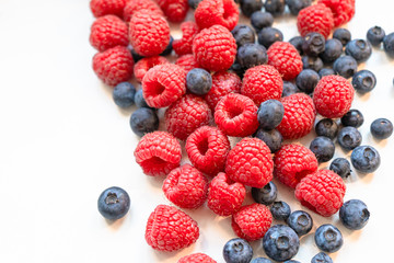 Closeup photo of freshly picked berries. On the photo there are a mix of berries: blueberry, wild strawberry and raspberry. Red, blue and purple colors on background