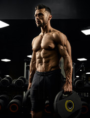 Fototapeta na wymiar Muscular male bodybuilder holding weights.