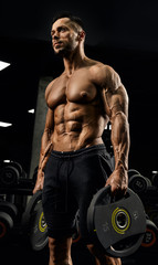 Fototapeta na wymiar Shirtless bodybuilder carrying weights.