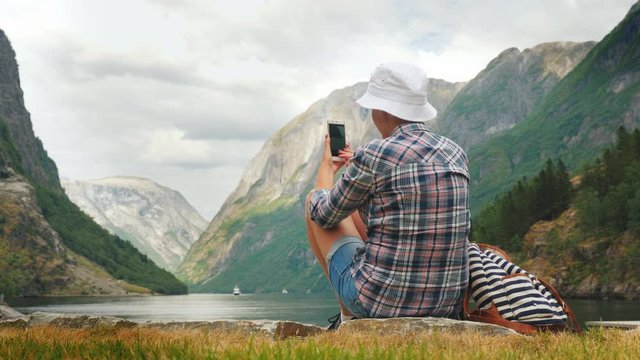 A traveler takes pictures of a picturesque fjord in Norway. Tourism in Scandinavia