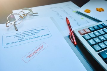 The reviewed financial statement, eyeglass, highlight pencil, calculator, laptop and edited paper. It's important work of the account, finance, internal and external audit must to accurate and timely