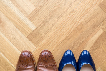 stylish leather shoes of a man and of a woman on wooden floor