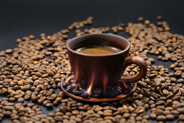 A cup of burning coffee on roasted coffee beans.