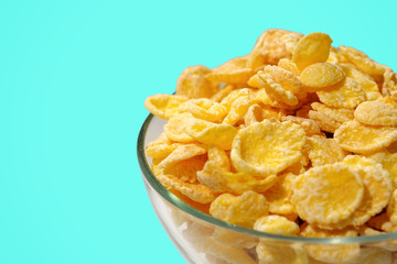 A bowl of cornflakes on a blue background. Close-up.