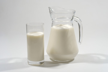 Glass and jug of fresh milk on a gray background. Dairy product.