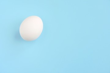 White chicken egg for Easter holiday on neutral light blue background. Raw organic egg. Easter eggs. Ingredients for healthy protein breakfast. Keto diet. Easter background traditional symbol