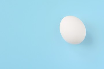 White chicken egg for Easter holiday on neutral light blue background. Raw organic egg. Easter eggs. Ingredients for healthy protein breakfast. Keto diet. Easter background traditional symbol
