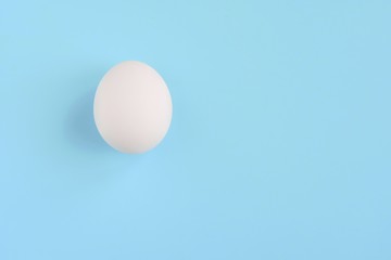 White chicken egg for Easter holiday on neutral light blue background. Raw organic egg. Easter eggs. Ingredients for healthy protein breakfast. Keto diet. Easter background traditional symbol