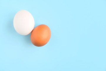 White and brown chicken eggs for Easter holiday on neutral light blue background. Raw organic egg. Easter eggs. Ingredients for healthy protein breakfast. Keto diet. Easter background 