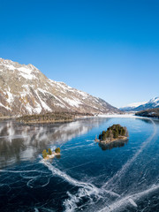 Obraz premium Aerial image of the Chaviolas islets on the frozen lake of Silsersee in St. Moritz, Switzerland
