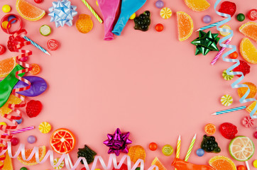 Flat lay view at sweetframe of different type color and taste candies and birthday candles on pink. Space for text