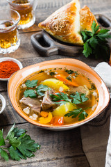Asian soup shurpa with meat and vegetables in plate on wooned table.