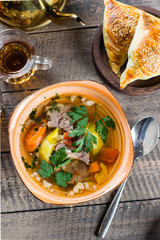 Asian soup shurpa with meat and vegetables in plate on wooned table. Top view