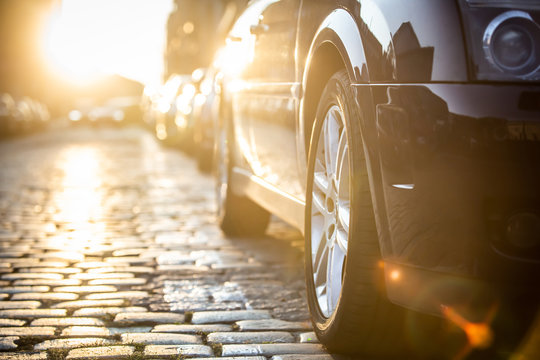 Cars parked on the side of the road, with sunset background.