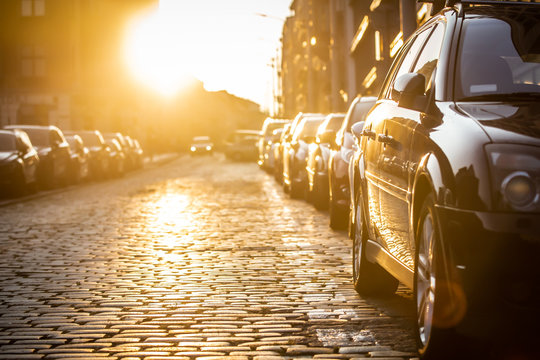 Cars parked on the side of the road, with sunset background.