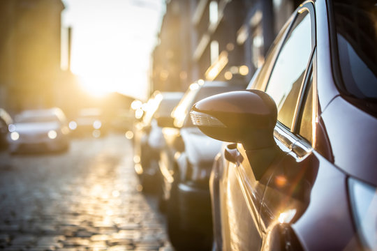 Cars parked on the side of the road, with sunset background.