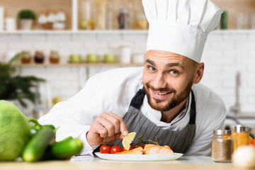 Professional Chef Man Plating Salmon Dish Working In Kitchen