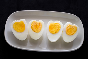 Heart shaped boiled eggs on the dish with black background