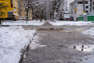Winter road for pedestrians cleaned from snow. Chemicals pour on a pedestrian path, the snow has melted. Frost, snow fell.
