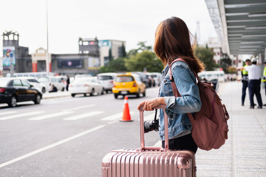 Young woman traveler with luggage looking for taxi at the Airport