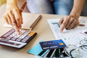 Young woman checking bills, taxes, bank account balance and calculating credit card expenses at home