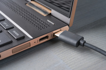 Closeup of USB Type C grey cable being connected to the laptop computer.
