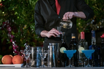 Bartender at night party, Bartender pouring the ingredients into a cocktail glass.