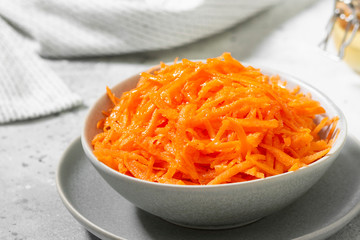 Carrots with honey in a gray bowl on a gray kitchen table. Food for vegetarians