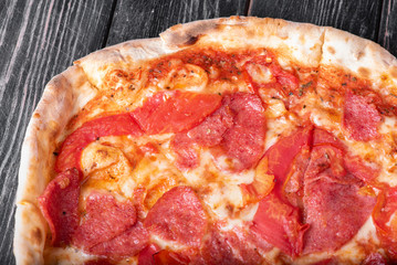 Pizza with salami  on wooden background.