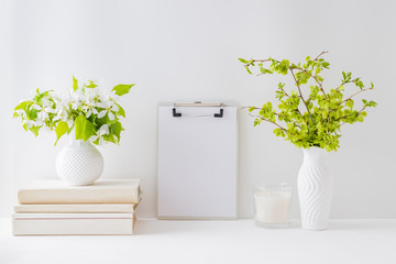 Home interior with decor elements. Mockup with a clipboard, spring flowers in a vase on a light background