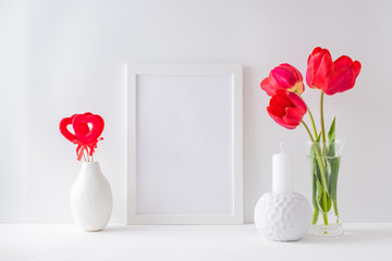 Home interior with decor elements. Mockup with a white frame, red tulips in a vase on a light background