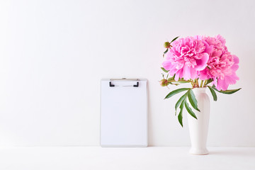 Mockup with a mockup clipboard and pink peonies in a vase on a white background