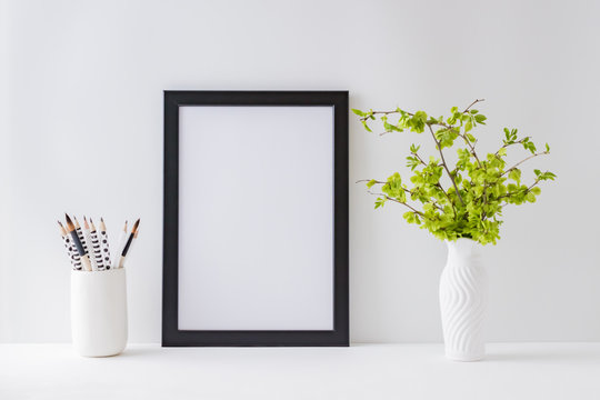 Home interior with decor elements. Mockup with a black frame, branches with green leaves on a light background