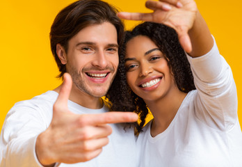 Romantic Multiracial Couple Framing Their Faces With Fingers And Smiling