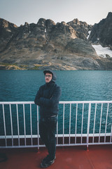 Good looking young man looking forward and smiling while standing on the deck of a ship in the Arctic. On Board Sarfaq Ittuk coastal ship in Greenland traveling from Ilulissat to Nuuk.