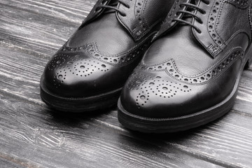 Black leather shoes against wooden background.