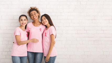 Three Girls In T-Shirts With Ribbons Standing Over White Wall