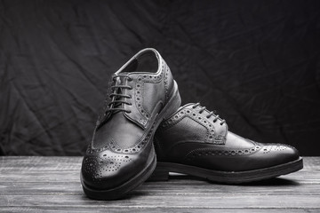 Black leather shoes against wooden background.