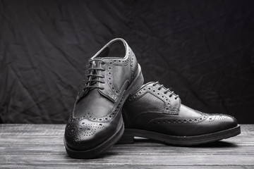 Fototapeta na wymiar Black leather shoes against wooden background.