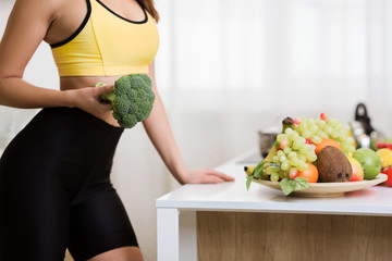 Healthy lifestyle. Woman holding broccoli and cooking after exercising