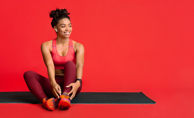 Happy fitness girl resting on yoga mat during training